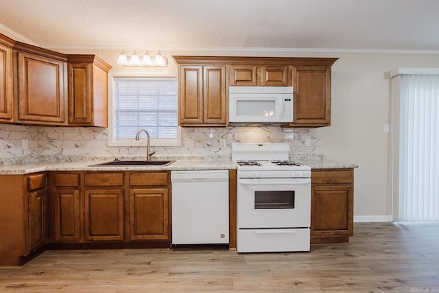 kitchen with sink, light wood-type flooring, crown molding, light stone countertops, and white appliances