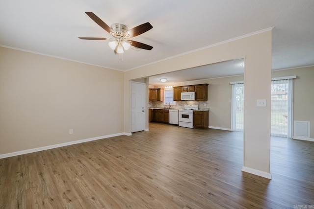 unfurnished living room with hardwood / wood-style flooring, ornamental molding, sink, and ceiling fan