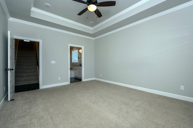 unfurnished bedroom featuring a tray ceiling, carpet floors, ornamental molding, and ceiling fan