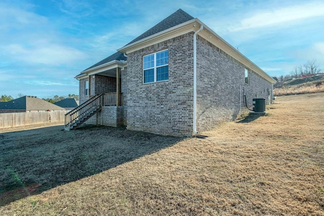 view of side of home with central AC unit and a yard