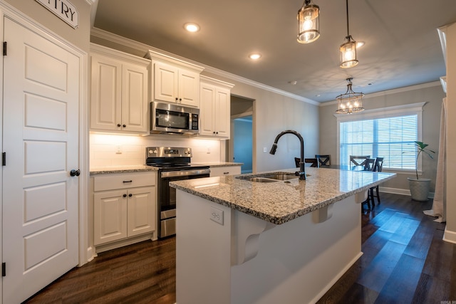 kitchen with pendant lighting, sink, appliances with stainless steel finishes, light stone countertops, and white cabinets