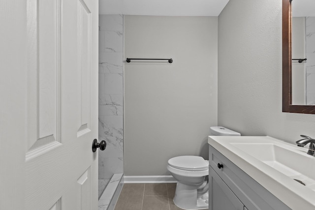 bathroom featuring vanity, tiled shower, tile patterned floors, and toilet