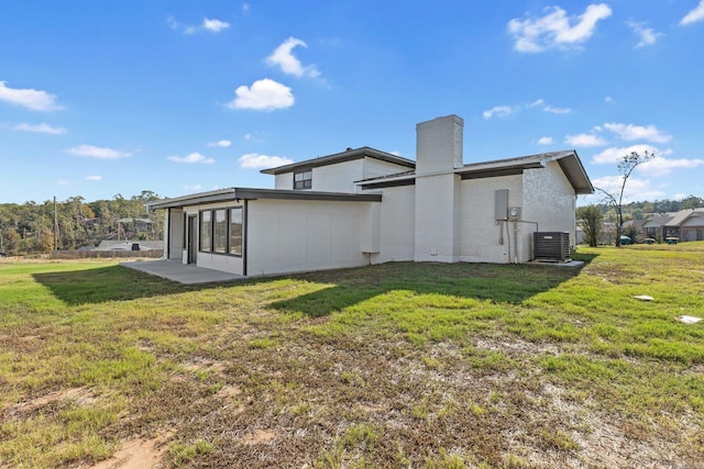 back of property featuring central AC unit, a patio area, and a lawn