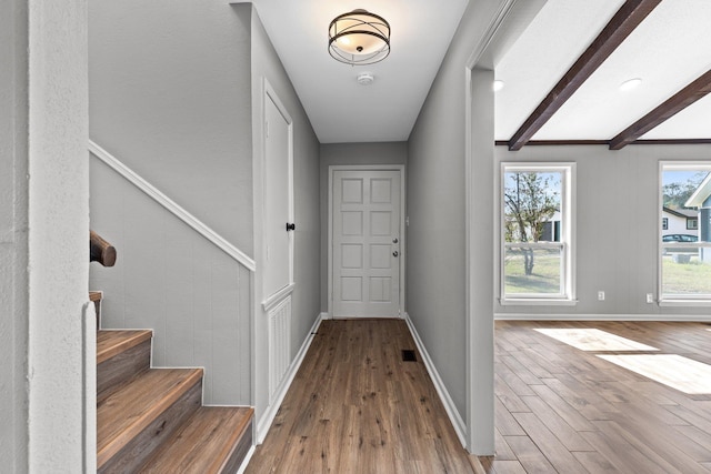 doorway to outside with beam ceiling and light hardwood / wood-style floors