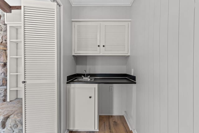 interior space featuring sink, hardwood / wood-style floors, white cabinets, and wooden walls