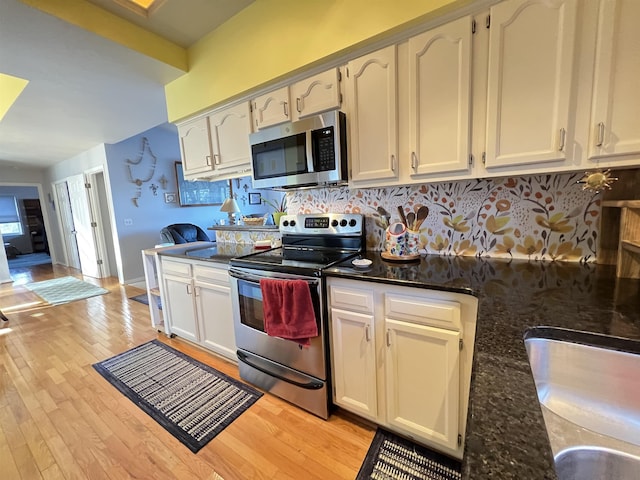 kitchen featuring dark stone countertops, decorative backsplash, light hardwood / wood-style floors, and appliances with stainless steel finishes