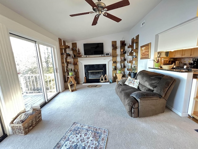 carpeted living room featuring vaulted ceiling, a tile fireplace, and ceiling fan