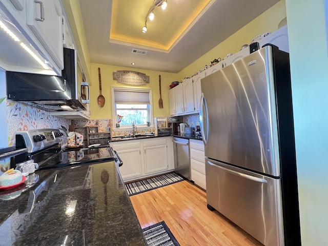 kitchen featuring appliances with stainless steel finishes, tasteful backsplash, sink, white cabinets, and a raised ceiling