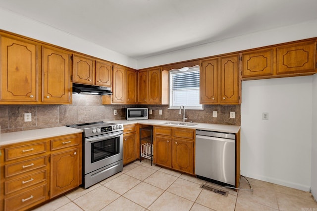 kitchen with sink, backsplash, light tile patterned flooring, and appliances with stainless steel finishes