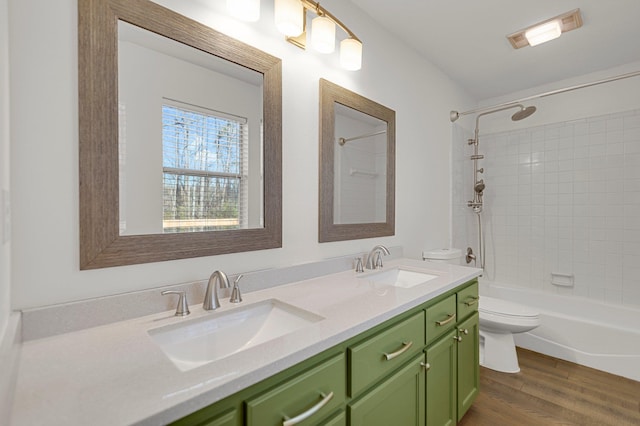 full bathroom featuring tiled shower / bath combo, vanity, hardwood / wood-style floors, and toilet