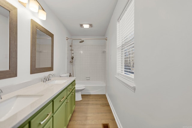 full bathroom featuring hardwood / wood-style flooring, vanity, tiled shower / bath combo, and toilet