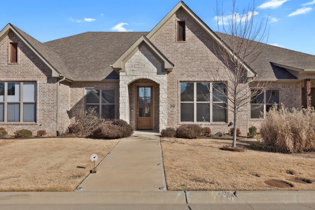 french country inspired facade featuring a front lawn