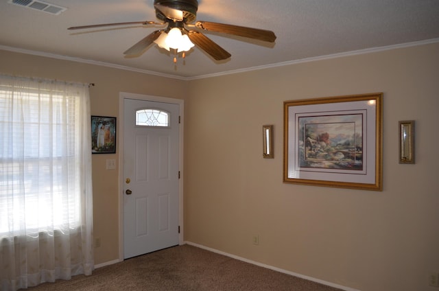 foyer with crown molding, ceiling fan, and carpet