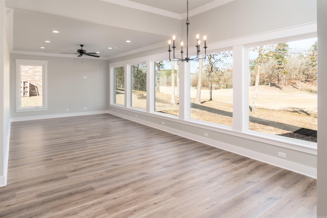 unfurnished dining area with ornamental molding, wood-type flooring, and ceiling fan with notable chandelier