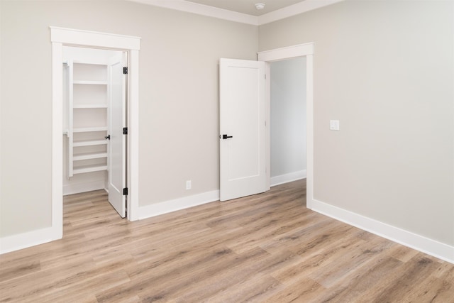 unfurnished bedroom with a spacious closet, a closet, and light wood-type flooring