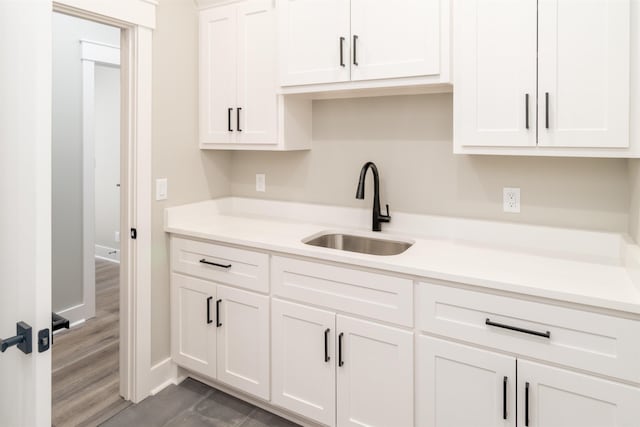 kitchen with dark hardwood / wood-style flooring, sink, and white cabinets