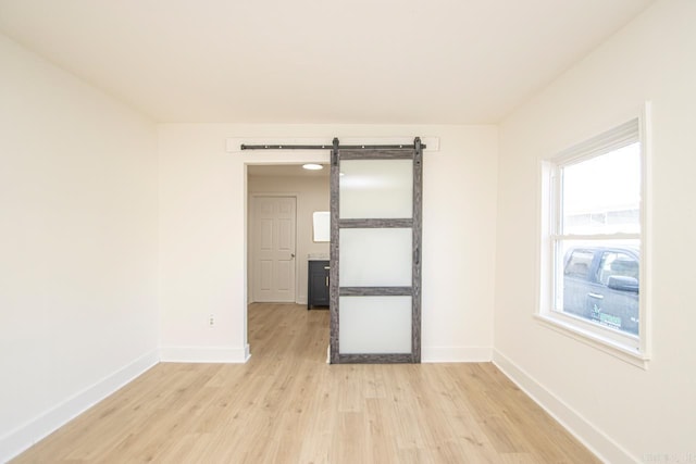 unfurnished room featuring a barn door and light wood-type flooring