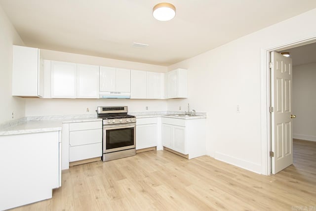 kitchen featuring sink, white cabinets, light hardwood / wood-style floors, and stainless steel gas stove