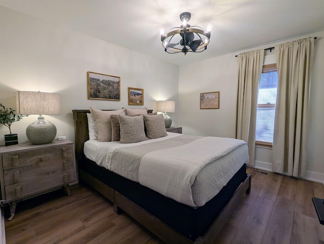 bedroom with dark wood-type flooring and a notable chandelier