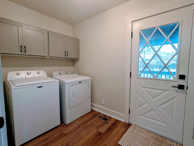 washroom with cabinets, washing machine and dryer, and dark hardwood / wood-style flooring