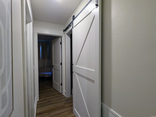 corridor featuring dark wood-type flooring and a barn door