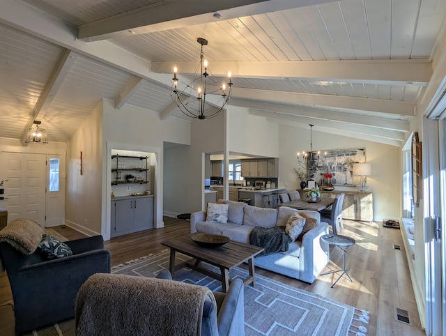 living room featuring a chandelier, lofted ceiling with beams, hardwood / wood-style floors, and a wealth of natural light