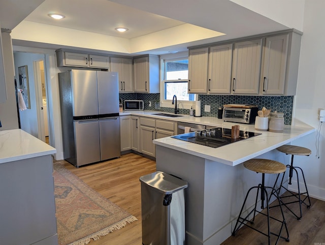 kitchen with gray cabinetry, sink, black appliances, and kitchen peninsula