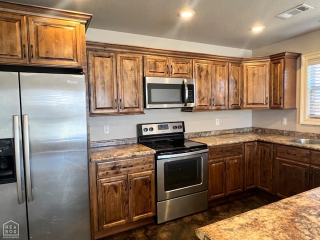 kitchen featuring stainless steel appliances, sink, and a textured ceiling