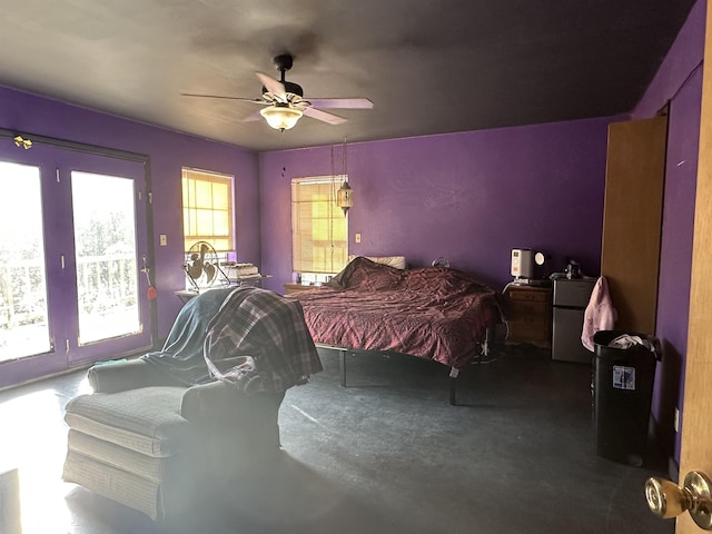 bedroom featuring fridge, ceiling fan, multiple windows, and concrete floors