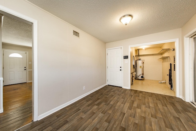 spare room with dark hardwood / wood-style floors, a textured ceiling, and gas water heater