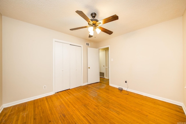 unfurnished bedroom featuring wood-type flooring, a textured ceiling, ceiling fan, and a closet