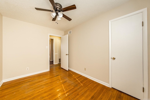 unfurnished bedroom featuring wood-type flooring, a textured ceiling, and ceiling fan