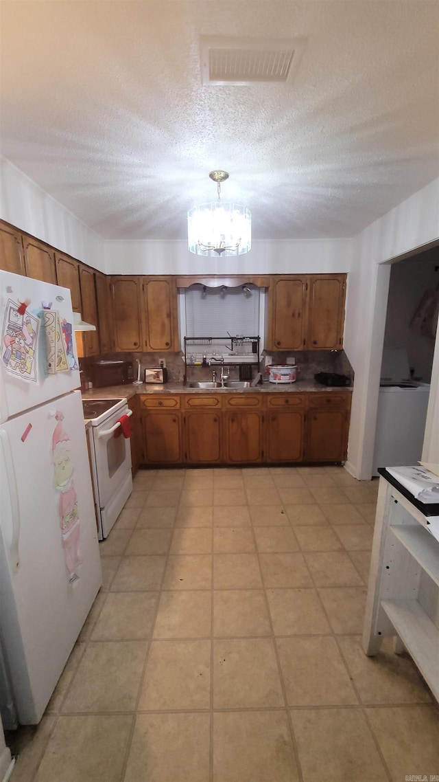 kitchen featuring a notable chandelier, sink, a textured ceiling, and white appliances