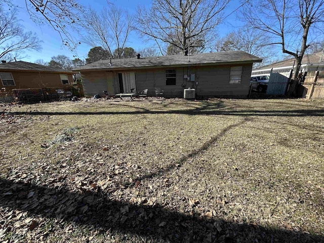 rear view of house featuring central AC unit and a lawn