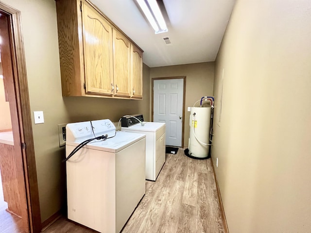 washroom with cabinets, light hardwood / wood-style flooring, water heater, and washing machine and clothes dryer