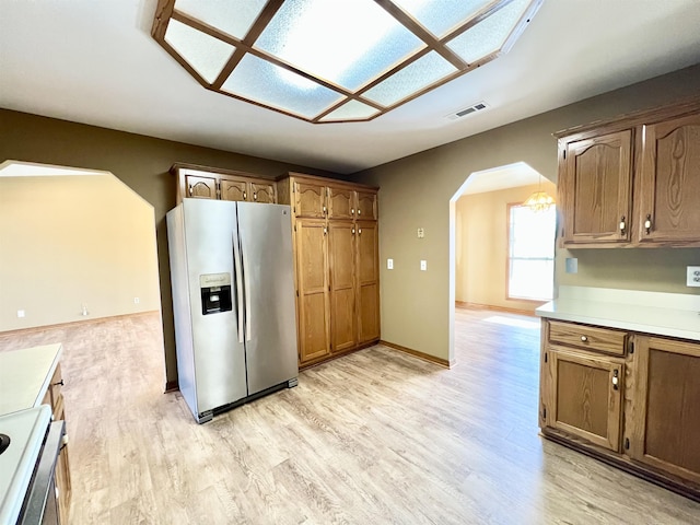 kitchen featuring stove, light wood-type flooring, and stainless steel refrigerator with ice dispenser