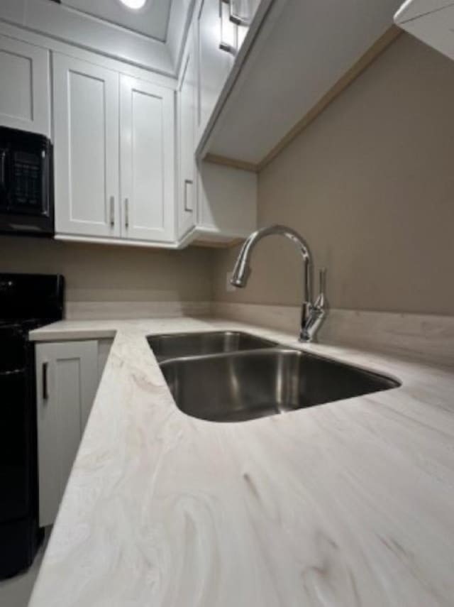 kitchen with sink, white cabinets, and black appliances