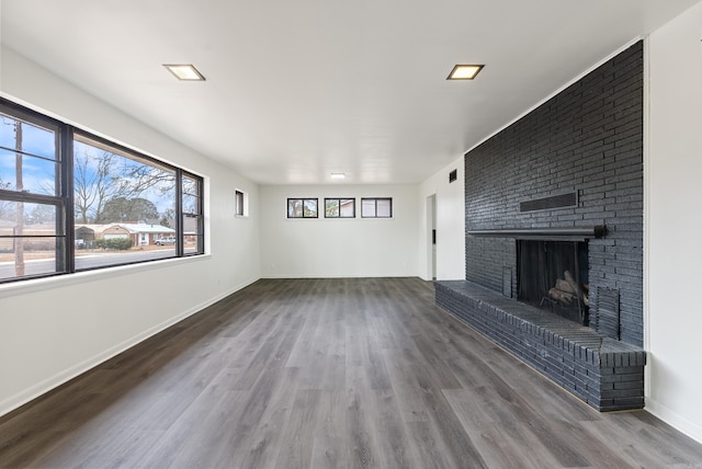 unfurnished living room featuring hardwood / wood-style floors and a brick fireplace