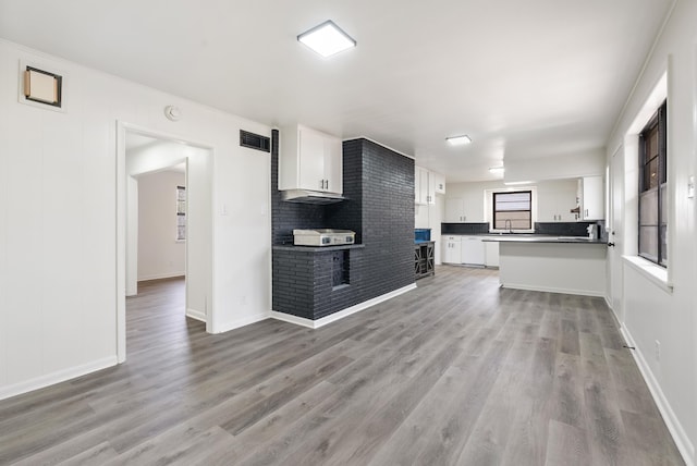 kitchen with sink, white cabinets, light wood-type flooring, and kitchen peninsula