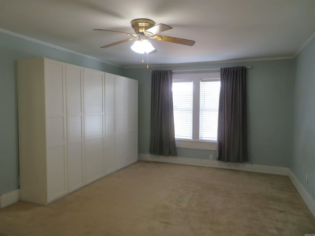 unfurnished bedroom with crown molding, light colored carpet, ceiling fan, and a closet