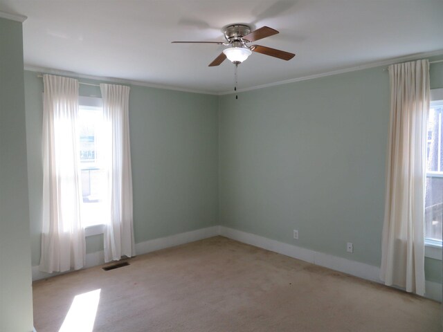 spare room featuring ornamental molding, light colored carpet, and ceiling fan