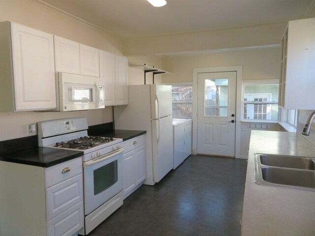 kitchen featuring white appliances, washing machine and clothes dryer, sink, and white cabinets