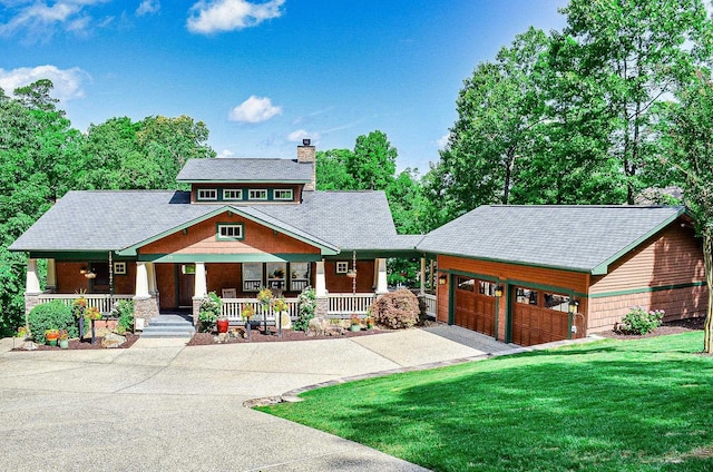 view of front of home with a garage, covered porch, and a front lawn