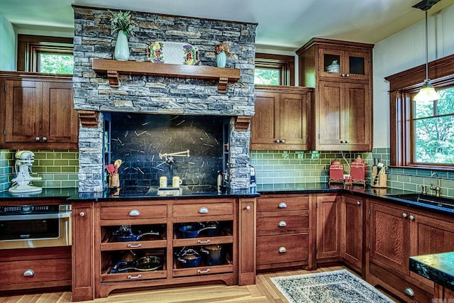 kitchen featuring a healthy amount of sunlight, sink, tasteful backsplash, and stainless steel oven