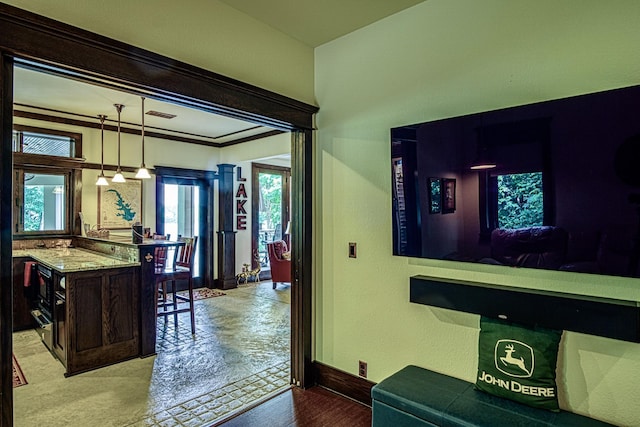 interior space with dark brown cabinetry, light stone counters, hanging light fixtures, ornamental molding, and light hardwood / wood-style floors