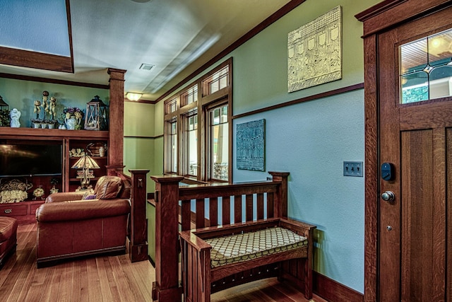 interior space with crown molding, light hardwood / wood-style floors, and ornate columns