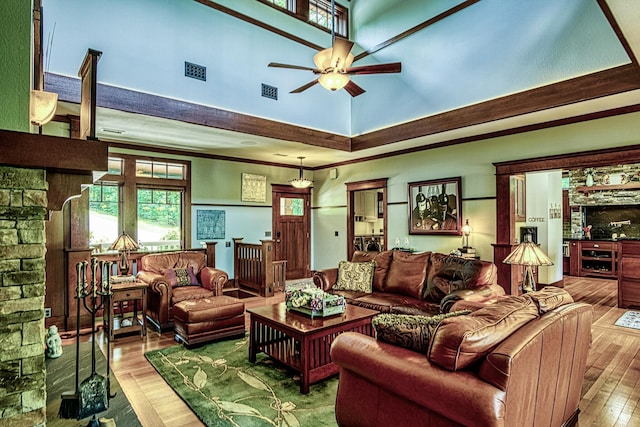 living room featuring ceiling fan, a towering ceiling, and hardwood / wood-style floors