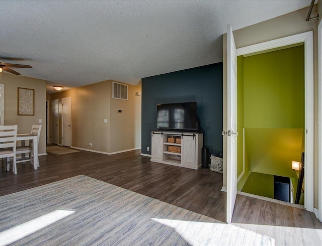 unfurnished living room featuring ceiling fan, wood-type flooring, and a textured ceiling