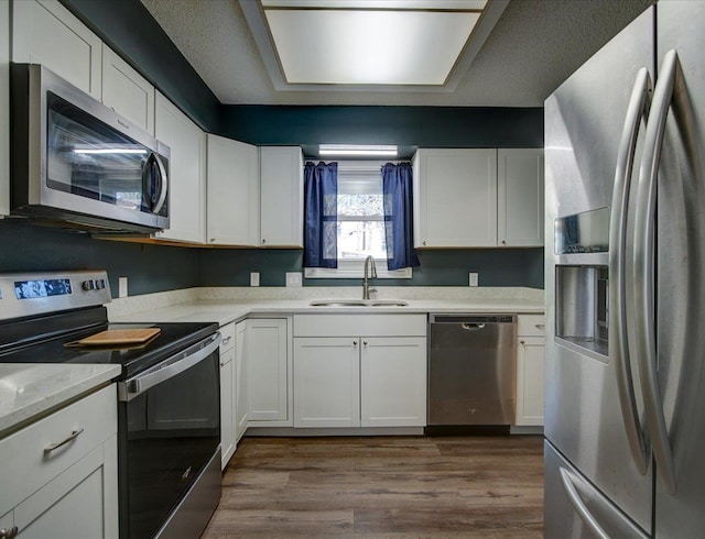 kitchen with dark wood-type flooring, appliances with stainless steel finishes, sink, and white cabinets