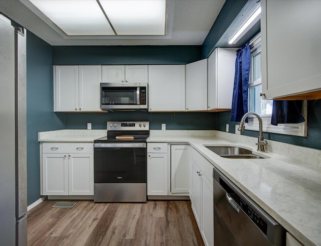 kitchen with sink, light hardwood / wood-style flooring, stainless steel appliances, and white cabinets